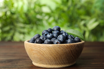 Tasty ripe blueberries in bowl on wooden table