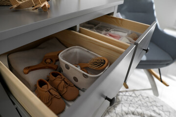 Obraz na płótnie Canvas Open cabinet drawer with baby shoes and accessories in child room