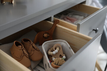 Fototapeta na wymiar Open cabinet drawer with baby shoes and accessories in child room