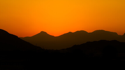Sunset mountains. Background with orange sky and mountains
