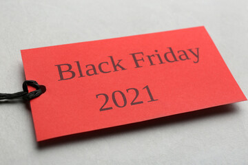 Red tag with words BLACK FRIDAY 2021 on light grey background, closeup