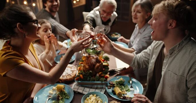 Large caucasian family celebrating thanksgiving day, making a toast and clinking their glasses, positively smiling - celebration concept 4k footage