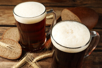 Mugs of delicious kvass, spikes and bread on wooden table