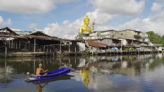 The Giant Golden Buddha in Wat Paknam Phasi Charoen Temple in Phasi Charoen district with boat on Chao Phraya River at sunset, Bangkok urban city, Thailand.