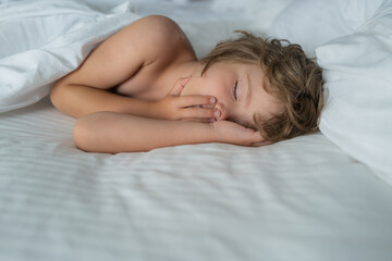 Healthy kids boy, sweetest blonde toddler kids sleeping in bed. Bedding linen and mattress in bedroom.