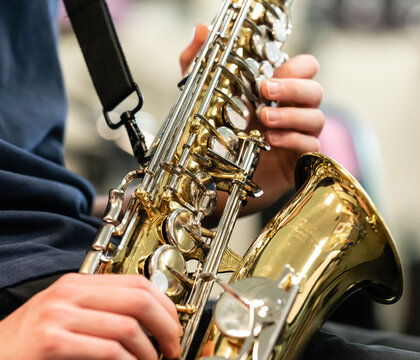 Midsection of boy playing saxophone in music class