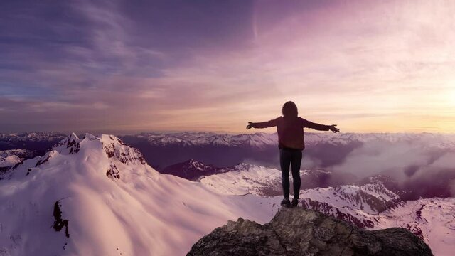 Fantasy Adventure Composite with a Girl on top of a Rock Cliff with Beautiful Canadian Mountain Nature Landscape in Background during Sunset. Parallax Panorama