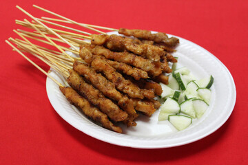 Satay or sate, skewered and grilled meat, served with cucumber. Traditional Malay food in Malaysia, Singapore and Indonesia