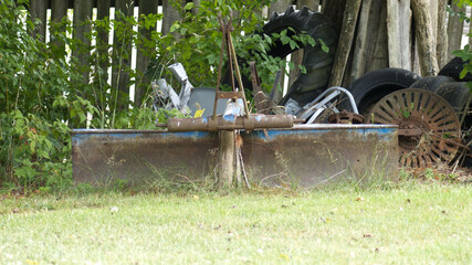 Old Farm Equipment Sitting in Front of an Old Wooden Fence