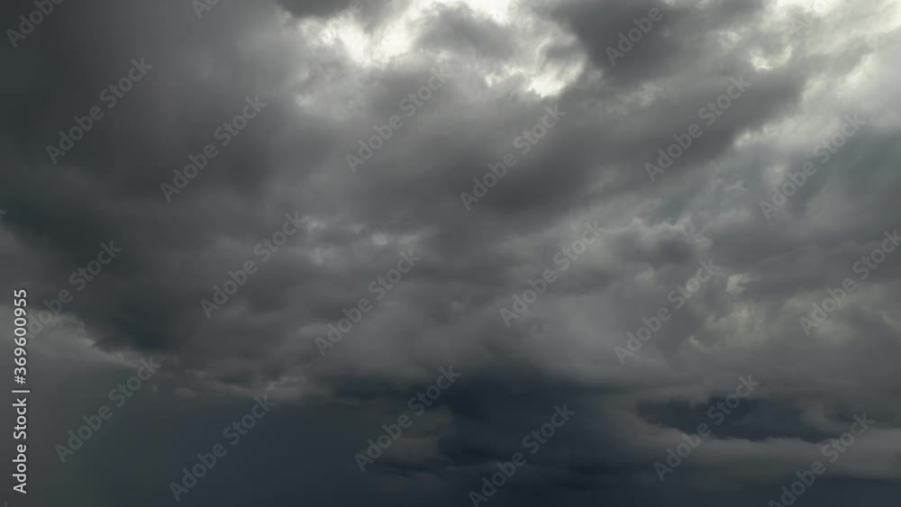 Wall mural feathery gray storm clouds churn and begin to dissipate in the overcast sky with sunlight lighting t