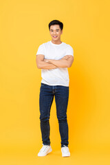 Fototapeta na wymiar Smiling young handsome Asian man standing with arms crossed gesture isolated on yellow studio background