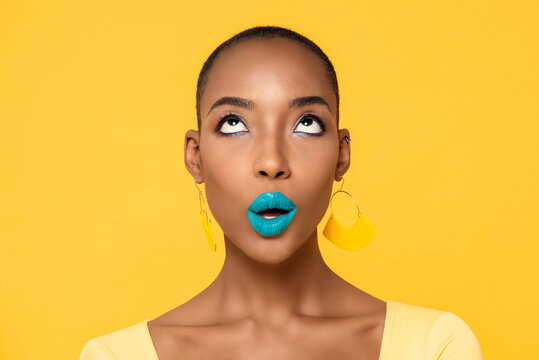 Close up portrait of beautiful young African American woman with fashionable colorful make up isolated on yellow studio background