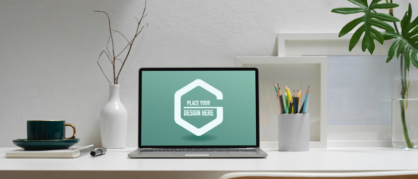 Modern workspace with mock up laptop, stationery, coffee cup and decorations on white table
