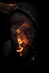 Halloween creepy man in shadow with hood and burning fire portrait. Demon possession with glowing...