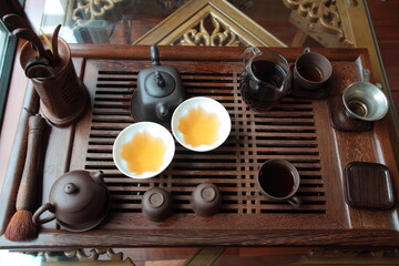 View of Traditional Chinese style tea set with Purple Clay Pots, tea cups and tea tools in a solid hardwood tea tray on table