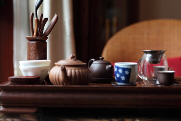 View of Traditional Chinese style tea set with Purple Clay Pots, tea cups and tea tools in a solid hardwood tea tray on table