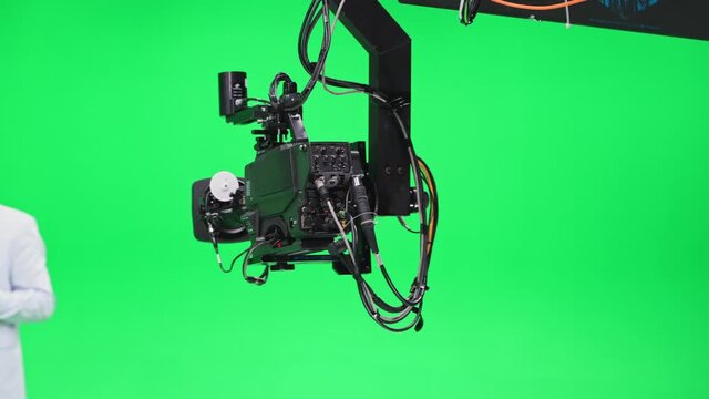 Film crew in green studio shooting video. Chroma - technology of combining two or more images or frames in single composition. Cameraman, director, crew. Filmmaking industry.