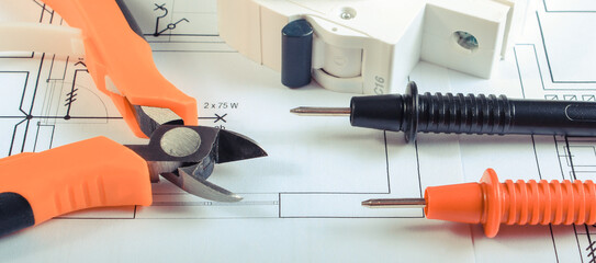 Cables of multimeter, pliers and electric fuse on construction drawing of house. Building home...