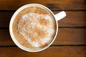 Coffee with cinnamon close-up on wooden background, top view
