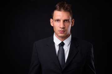 Portrait of businessman in suit against black background