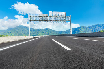 Asphalt highway and green mountain under blue sky.