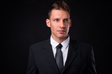 Portrait of businessman in suit against black background