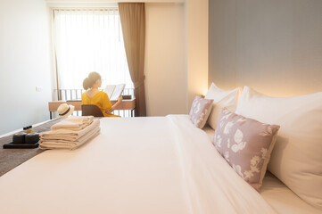 Tourist woman reading book in bedroom after check-in and arrival at a hotel. Conceptual of comfortable accommodation while tourist travel during their holiday and vacation time.