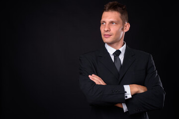 Portrait of businessman in suit against black background