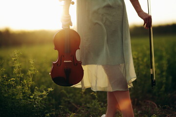Violin in the hands of a young female violinist in the sunset light. woman, girl