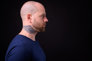 Handsome bald bearded man against black background