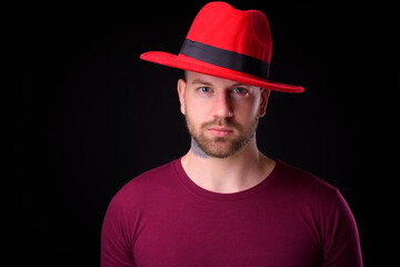 Handsome bearded man wearing hat against black background