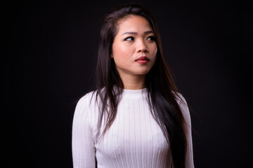 Fototapeta premium Portrait of young beautiful Asian woman against black background