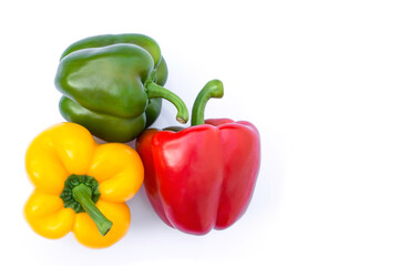 Pile of fresh whole green, red, yellow bell peppers or capsicum isolated on white background.