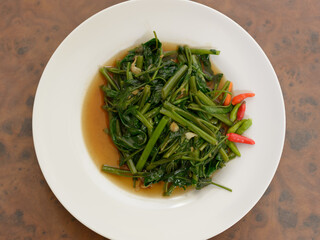 Stir fried water spinach on wooden table