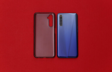 Smartphone with a silicone protective cover on red background. Top view