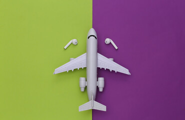 Air Plane and wireless headphones on a purple-green background. Top view