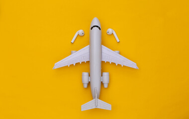 Air Plane and wireless headphones on yellow background. Top view
