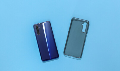 Smartphone and silicone protective cover on blue background. Top view