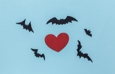 Red heart with bats and spiders on blue bright background. Halloween theme. Top view