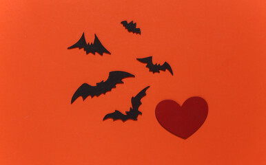 Naklejka premium Red heart with bats and spiders on orange bright background. Halloween theme. Top view