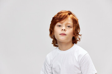 Cute redhead boy in white t-shirt close-up gray isolated 