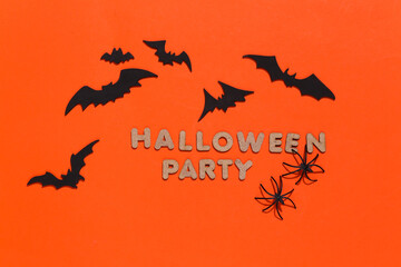 Bats and spiders on bright orange background with the word Halloween party. Halloween theme. Top view