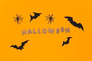 Bats and spiders on yellow background with word Halloween. Halloween theme. Top view