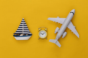 Mini alarm clock and ship, air plane on a yellow background. Time to travel. Top view