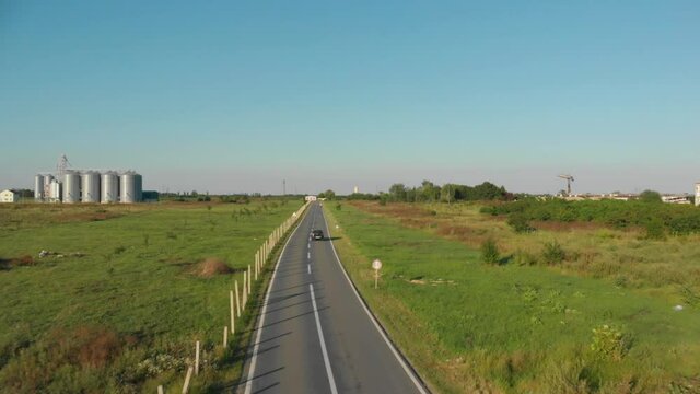 Aerial pan up following a car driving quickly on a road in the countryside near Novi Becej, Serbia.