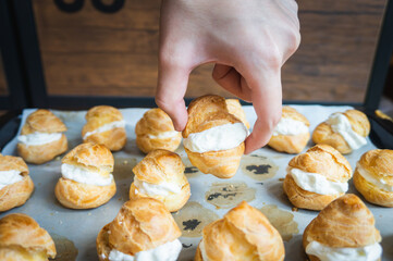 A hand picking up one golden cream puff 