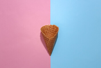 Ice cream waffle cone on pink and blue bright pastel background with deep shadow, top view. Flat lay minimal composition