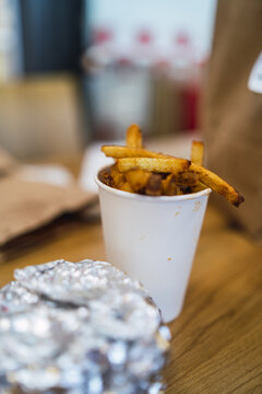 Vertical Shot Of A Fries On A Container With A Burger Wrapped With Foil