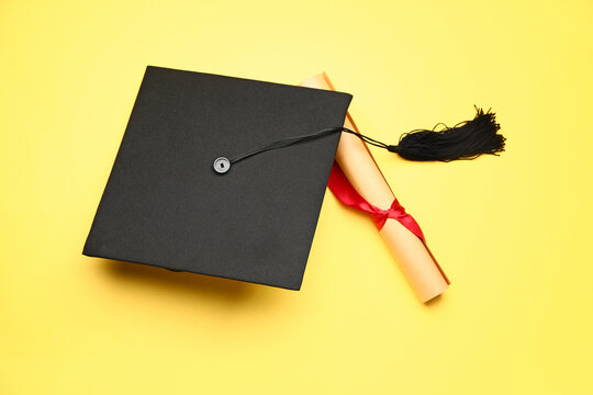 Graduation hat and diploma on color background