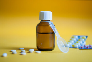 Cough syrup. Cold medicine. Pills and medicine on a yellow background. Pharmaceutical preparations...
